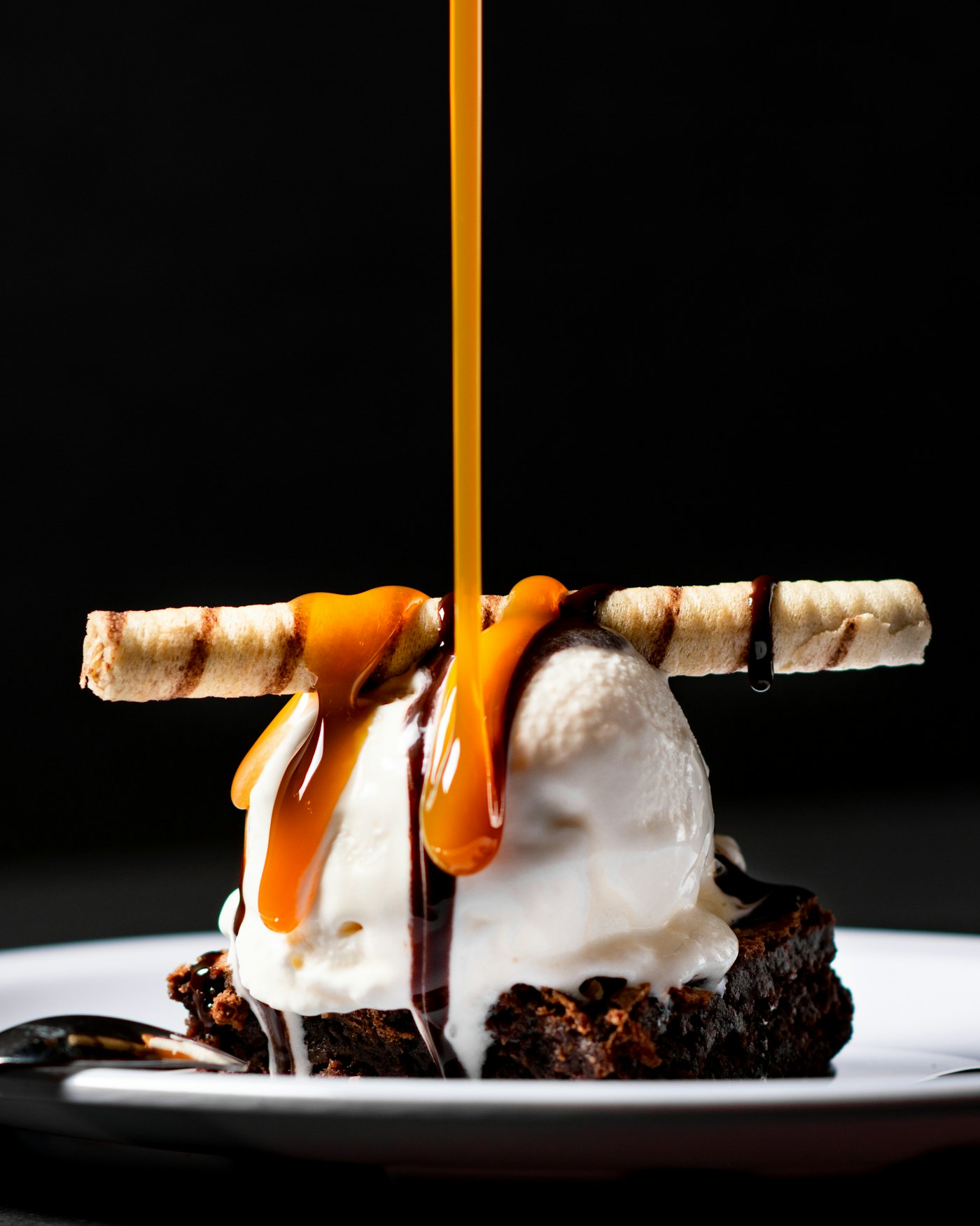 A warm brownie with ice cream and a pour of caramel