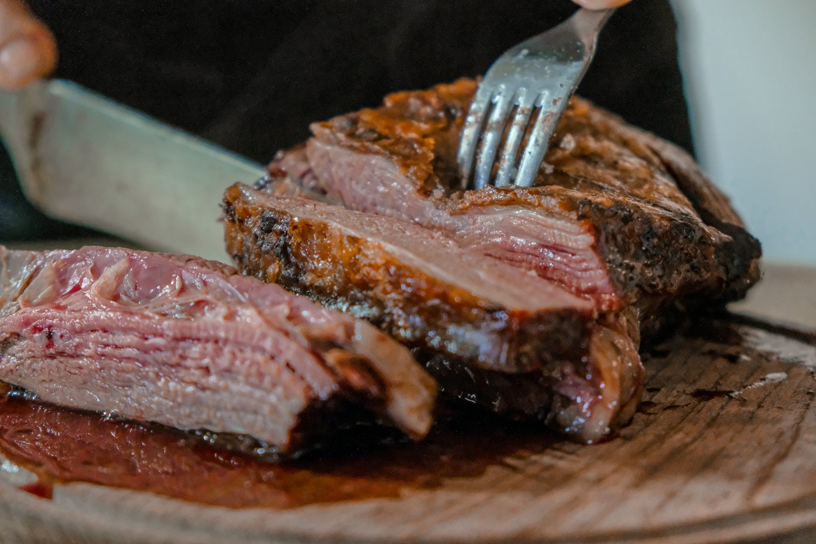 A perfectly rare steak being carved at the table